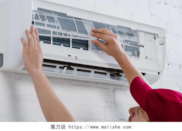 专业修理工的特写镜头挂在白砖墙上的空调更换过滤器
